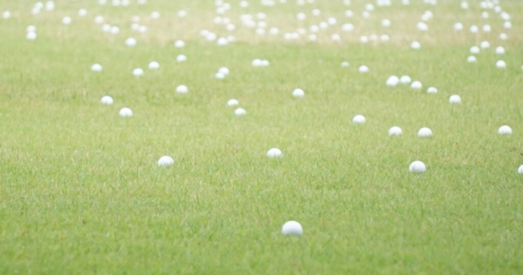 練習場の芝に転がるたくさんのゴルフボールのイメージ
