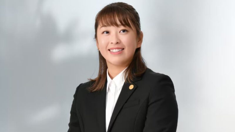 西郷真央選手がスーツ姿で微笑んでいる様子